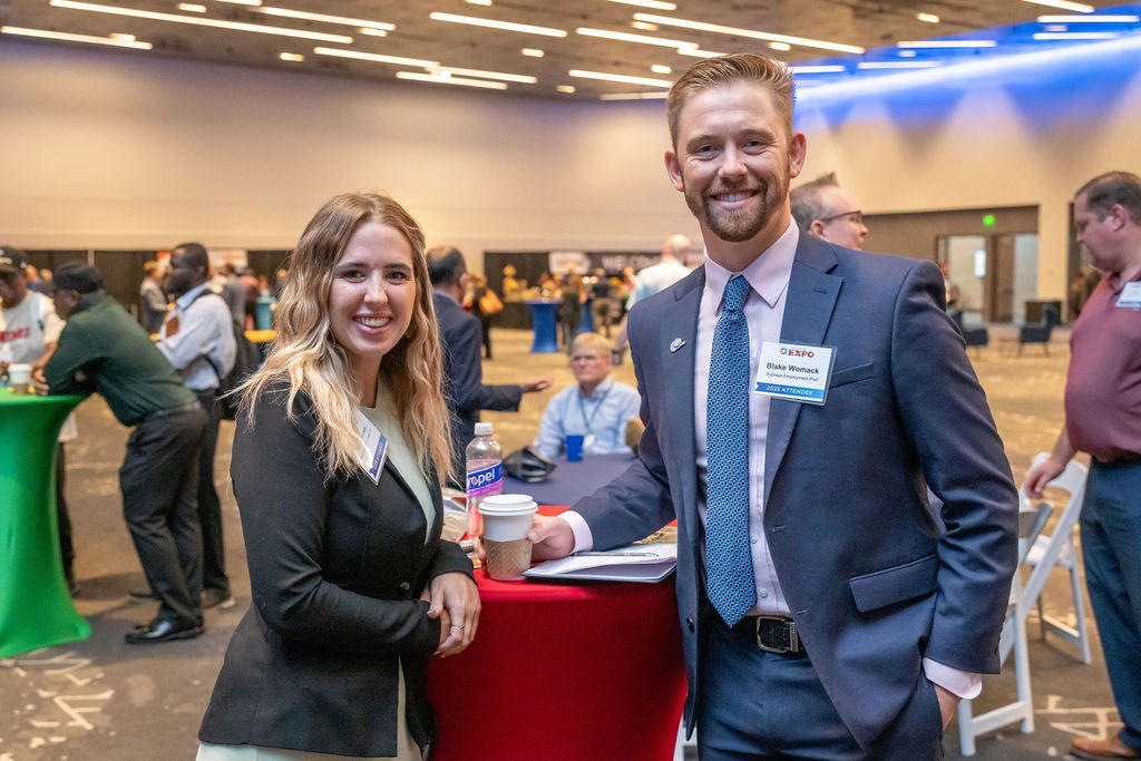 Two attendees smile at bistro table