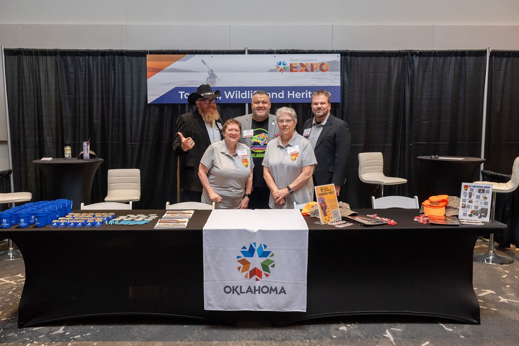 State staff smiling at Tourism, Wildlife and Heritage booth