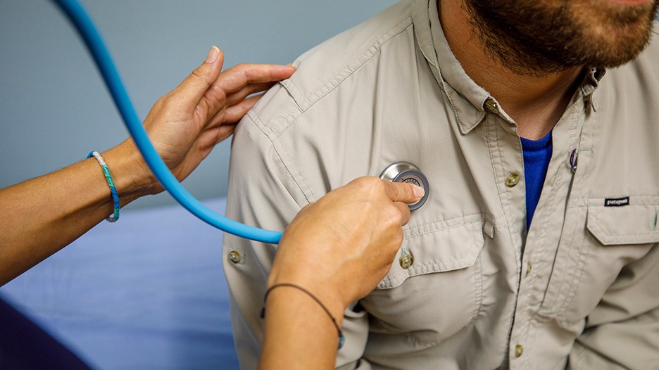 Patient with a stethoscope to their chest being examined by a doctor. 